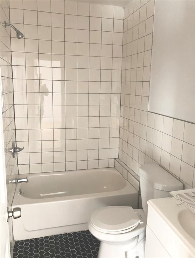 full bathroom with tile patterned flooring, toilet, tile walls, and tiled shower / bath