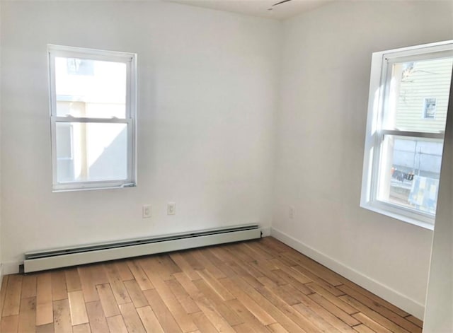 spare room featuring light wood-type flooring, baseboard heating, and a wealth of natural light