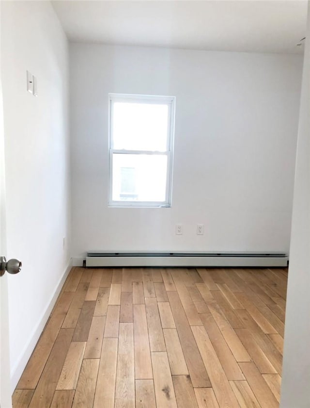 empty room with a baseboard radiator and light hardwood / wood-style flooring