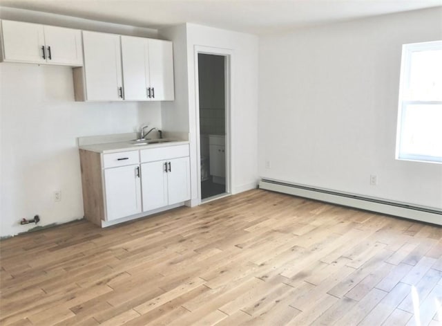 kitchen with baseboard heating, sink, white cabinets, and light hardwood / wood-style floors