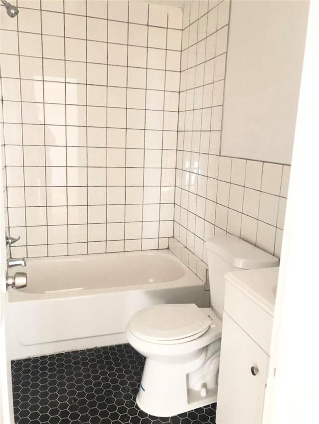 full bathroom featuring tile patterned floors, toilet, vanity, tile walls, and tiled shower / bath