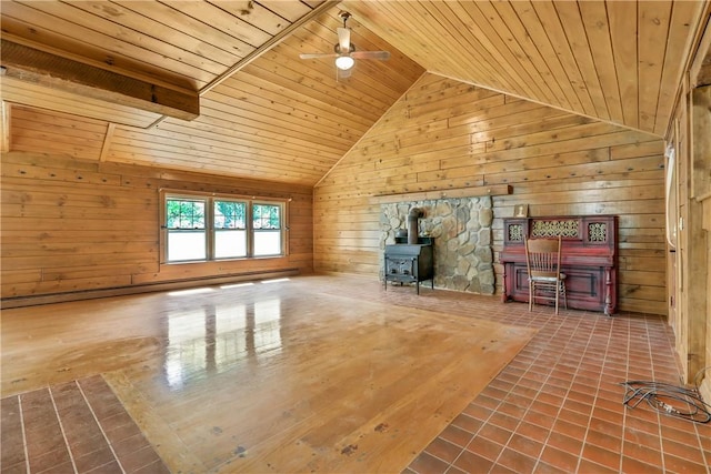 unfurnished living room with wood ceiling, ceiling fan, wooden walls, high vaulted ceiling, and a wood stove