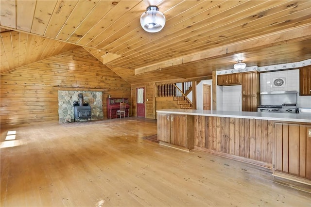 kitchen featuring light hardwood / wood-style flooring, a wood stove, wooden ceiling, and wood walls