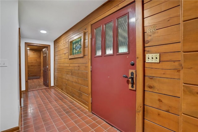 doorway featuring wood walls and dark tile patterned floors