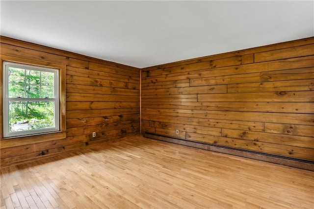 spare room featuring wood walls and light hardwood / wood-style floors