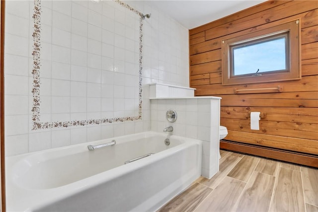 bathroom featuring hardwood / wood-style floors, wooden walls, a washtub, toilet, and a baseboard radiator