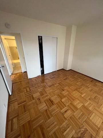 unfurnished bedroom with connected bathroom and light parquet flooring