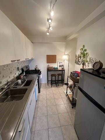 kitchen with stainless steel fridge, stove, white cabinets, and sink