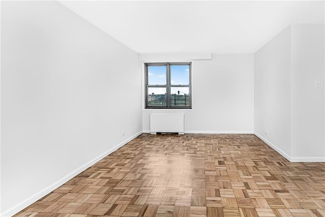 unfurnished room with radiator heating unit and light parquet flooring