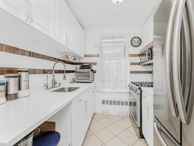 kitchen with sink, white cabinets, light tile patterned flooring, and appliances with stainless steel finishes