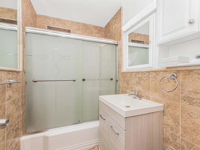 bathroom featuring tasteful backsplash, vanity, bath / shower combo with glass door, and tile walls