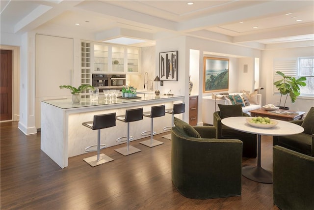 dining area featuring beam ceiling, sink, and dark hardwood / wood-style floors