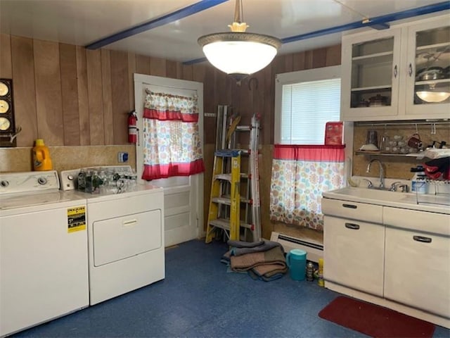 washroom with baseboard heating, washer and clothes dryer, wooden walls, and sink