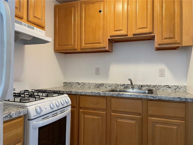 kitchen featuring light stone counters, white range with gas stovetop, and sink