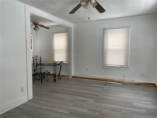 empty room with wooden walls, a healthy amount of sunlight, and hardwood / wood-style flooring