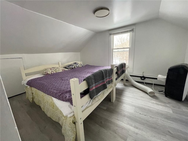 bedroom featuring hardwood / wood-style floors, a baseboard heating unit, and vaulted ceiling