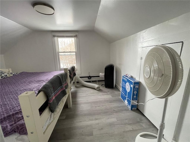 bedroom with hardwood / wood-style flooring, vaulted ceiling, and a baseboard heating unit