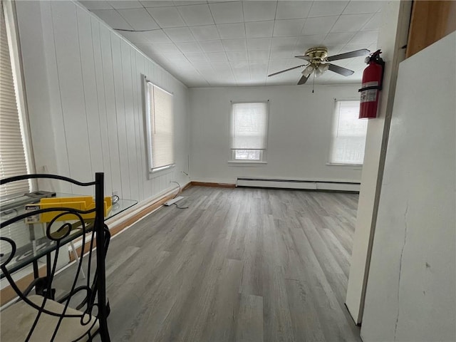 spare room featuring ceiling fan, light hardwood / wood-style floors, and a baseboard heating unit