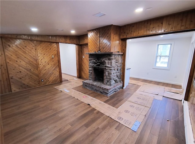 unfurnished living room featuring wood walls, a fireplace, and hardwood / wood-style flooring