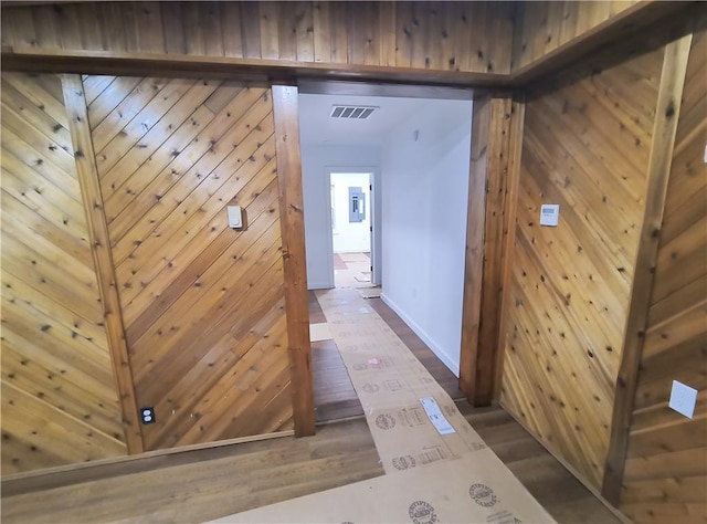 corridor featuring wooden walls and dark wood-type flooring