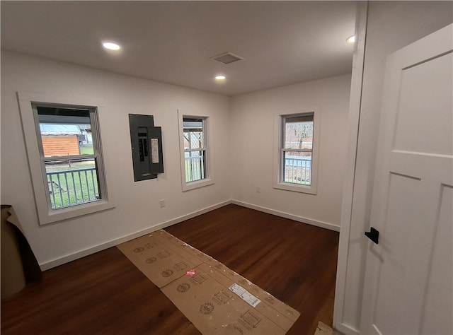 spare room featuring electric panel and dark hardwood / wood-style floors