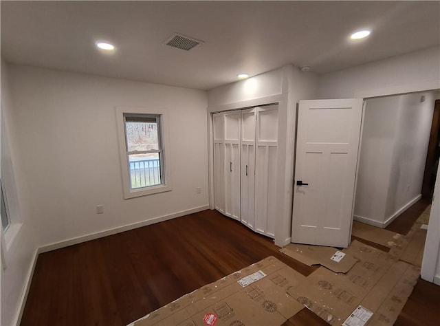 unfurnished bedroom featuring a closet and dark wood-type flooring