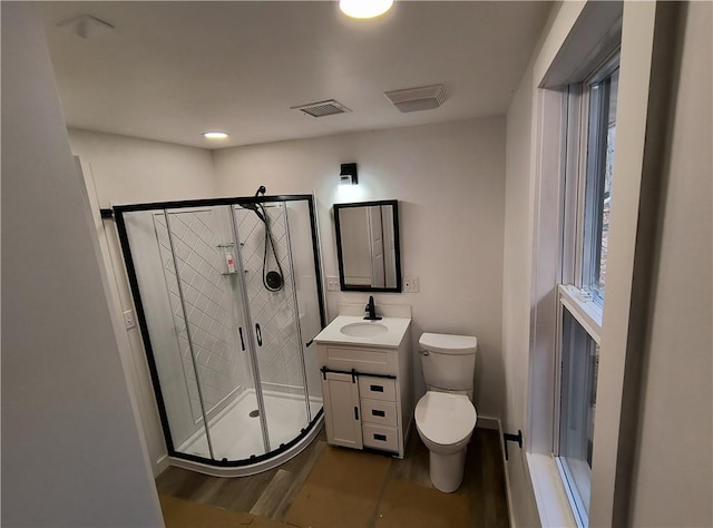 bathroom with hardwood / wood-style floors, vanity, an enclosed shower, and toilet