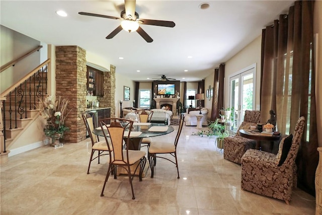 dining room with ceiling fan, a large fireplace, and french doors