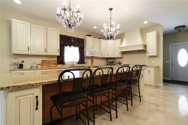 kitchen featuring custom range hood, light stone counters, a kitchen breakfast bar, and a large island