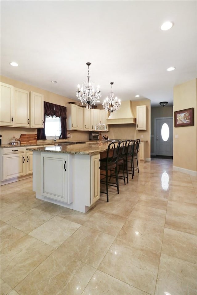 kitchen with pendant lighting, a center island, premium range hood, dark stone countertops, and a kitchen bar