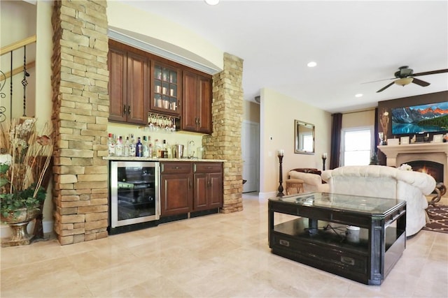 bar featuring dark brown cabinets, beverage cooler, and ceiling fan