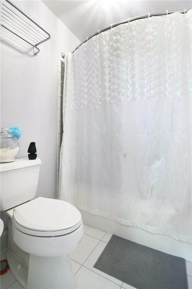 bathroom featuring tile patterned floors, a shower with shower curtain, and toilet