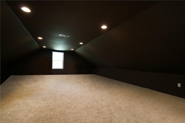 additional living space featuring vaulted ceiling and dark colored carpet