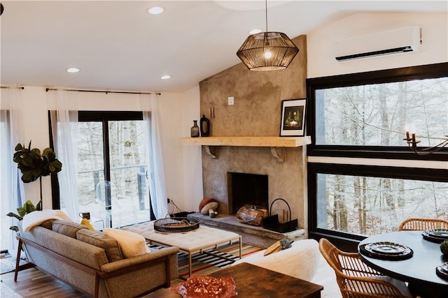 living room featuring an AC wall unit, hardwood / wood-style floors, a high end fireplace, and vaulted ceiling