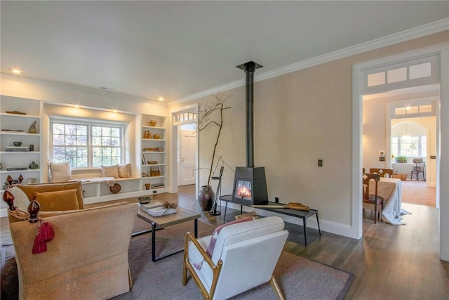 living room with plenty of natural light, wood-type flooring, a wood stove, and crown molding