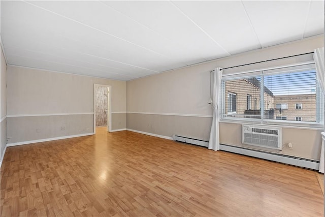 unfurnished room with light hardwood / wood-style floors, an AC wall unit, and a baseboard heating unit