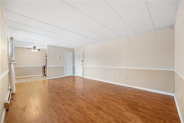 empty room with hardwood / wood-style floors, ceiling fan, and baseboard heating