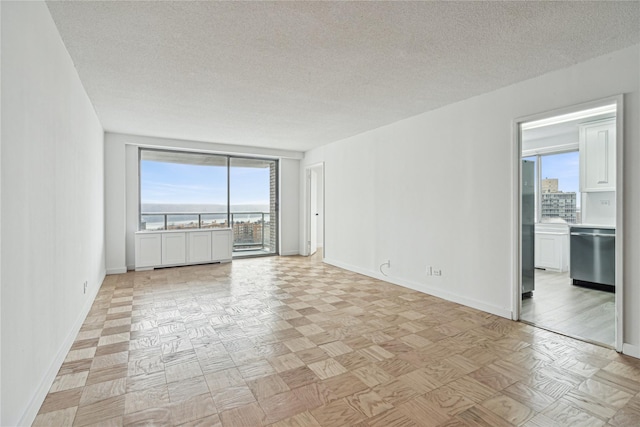 unfurnished room with a textured ceiling and light parquet floors