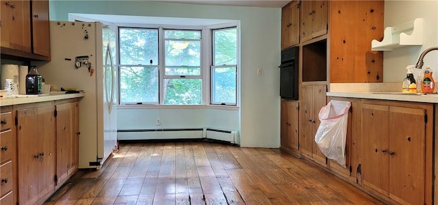 kitchen featuring hardwood / wood-style flooring, plenty of natural light, a baseboard heating unit, and sink