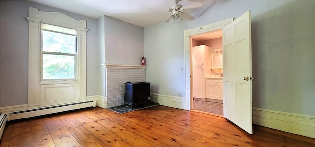 unfurnished living room with light wood-type flooring, ceiling fan, and a baseboard heating unit