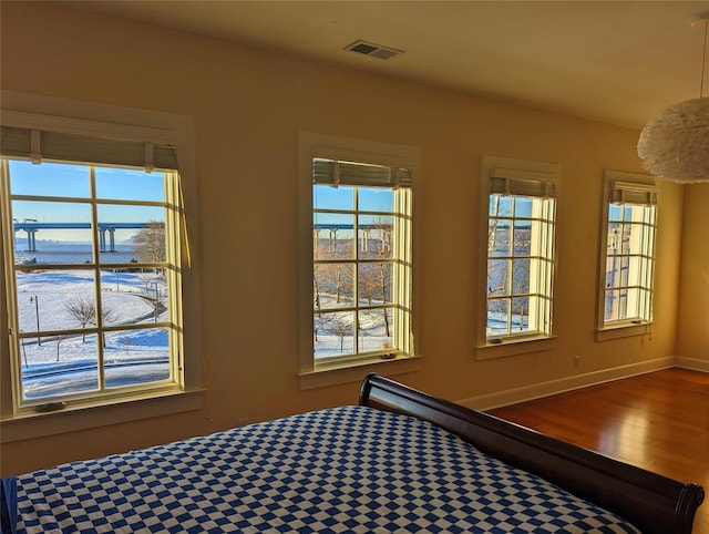 bedroom featuring a water view, baseboards, visible vents, and wood finished floors