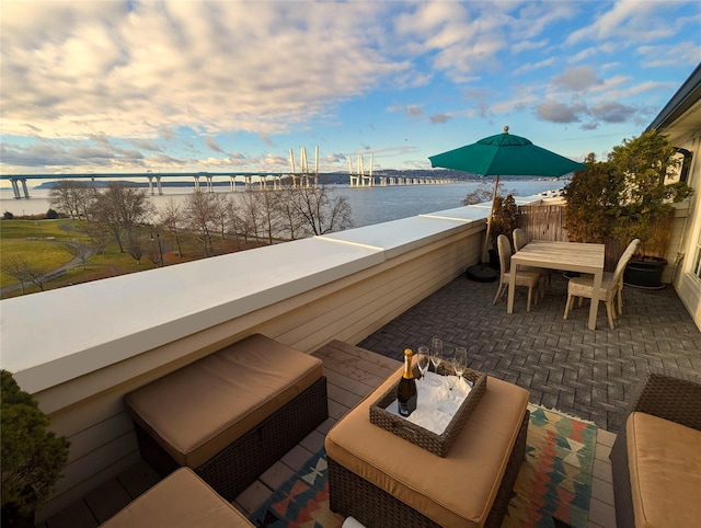 view of patio featuring a water view, a balcony, and outdoor dining space