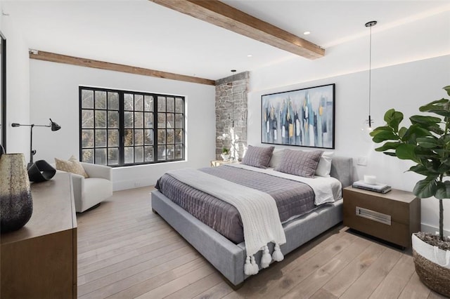 bedroom featuring beam ceiling and light hardwood / wood-style floors