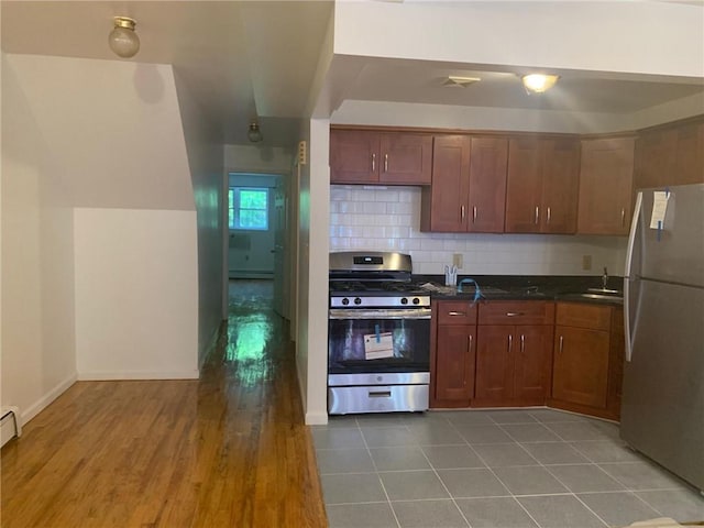 kitchen with appliances with stainless steel finishes, backsplash, sink, hardwood / wood-style flooring, and a baseboard radiator