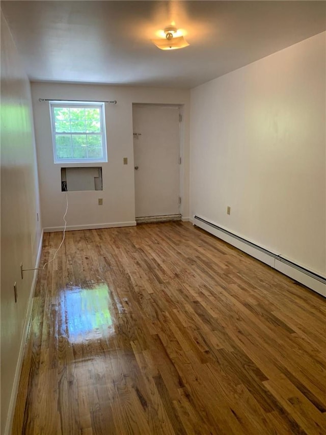 spare room with hardwood / wood-style flooring and a baseboard radiator