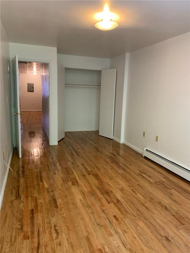 unfurnished bedroom with a closet, hardwood / wood-style floors, and a baseboard radiator