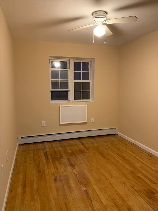 spare room featuring a baseboard radiator, ceiling fan, and light hardwood / wood-style floors