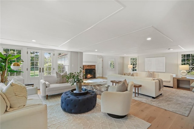 living room featuring light hardwood / wood-style floors, a fireplace, and french doors