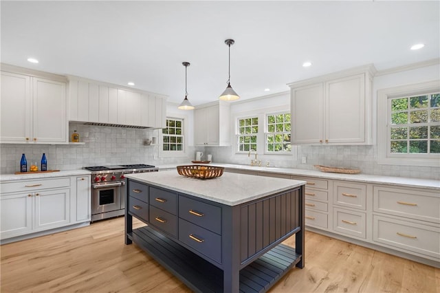 kitchen featuring white cabinets, light hardwood / wood-style floors, high end range, and hanging light fixtures