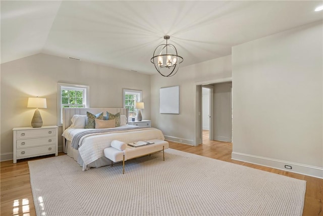 bedroom featuring light hardwood / wood-style flooring, vaulted ceiling, and an inviting chandelier